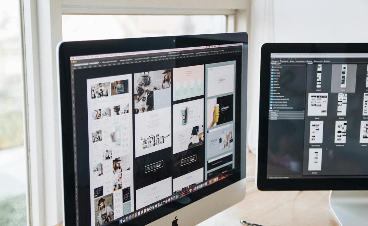 Zwei Desktop-Computer mit verschiedenen Website-Layouts in einer professionellen digitalen Arbeitsumgebung